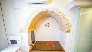A room with a stone arch, a small table, and a glass door. - Nivèra White Allure Maison · Suite Flùa – Ostuni (Ostuni)