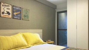 A hotel room with a bed, a nightstand, and a wall with vintage posters. - La Fleur Polinésia Residence & Resort (Ipojuca)