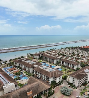 Un complejo turístico con varias construcciones, una playa y una piscina.