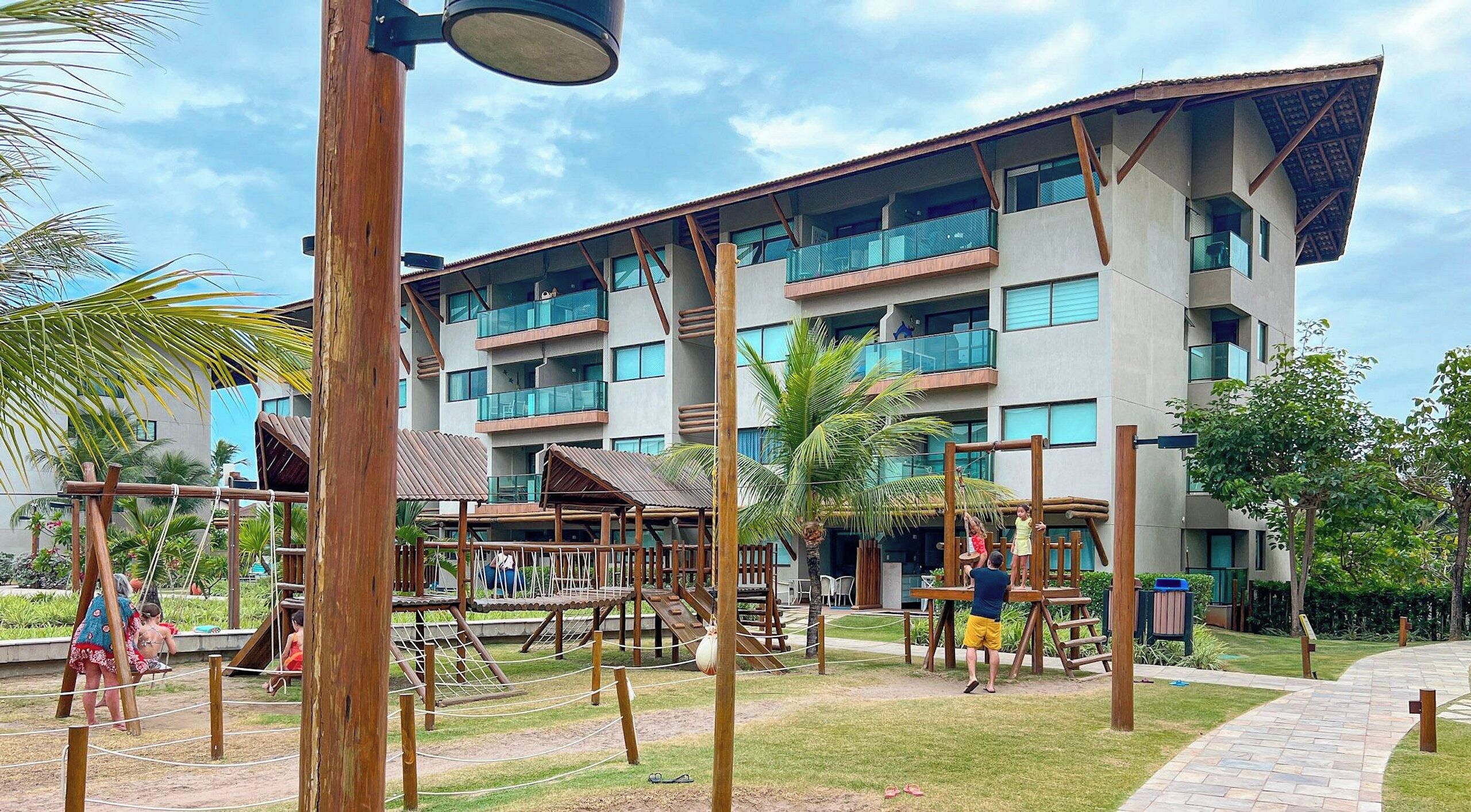Um hotel com vários andares e uma área de recreação, incluindo balanços e estruturas para escalar.