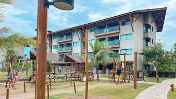 Um hotel com vários andares e uma área de recreação, incluindo balanços e estruturas para escalar.