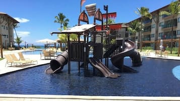 Uma área de piscina com um toboágua e espreguiçadeiras.