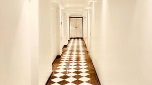 A long, narrow hallway with white walls and a checkered floor pattern. - Pride Landmark Plaza Near Delhi Airport (New Delhi)