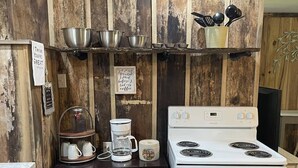 A kitchen with a white stove, wooden wall paneling, and various kitchen utensils and appliances.