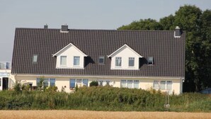 Een tweelaags huis met een donker dak, witte muren en een kleine veranda.