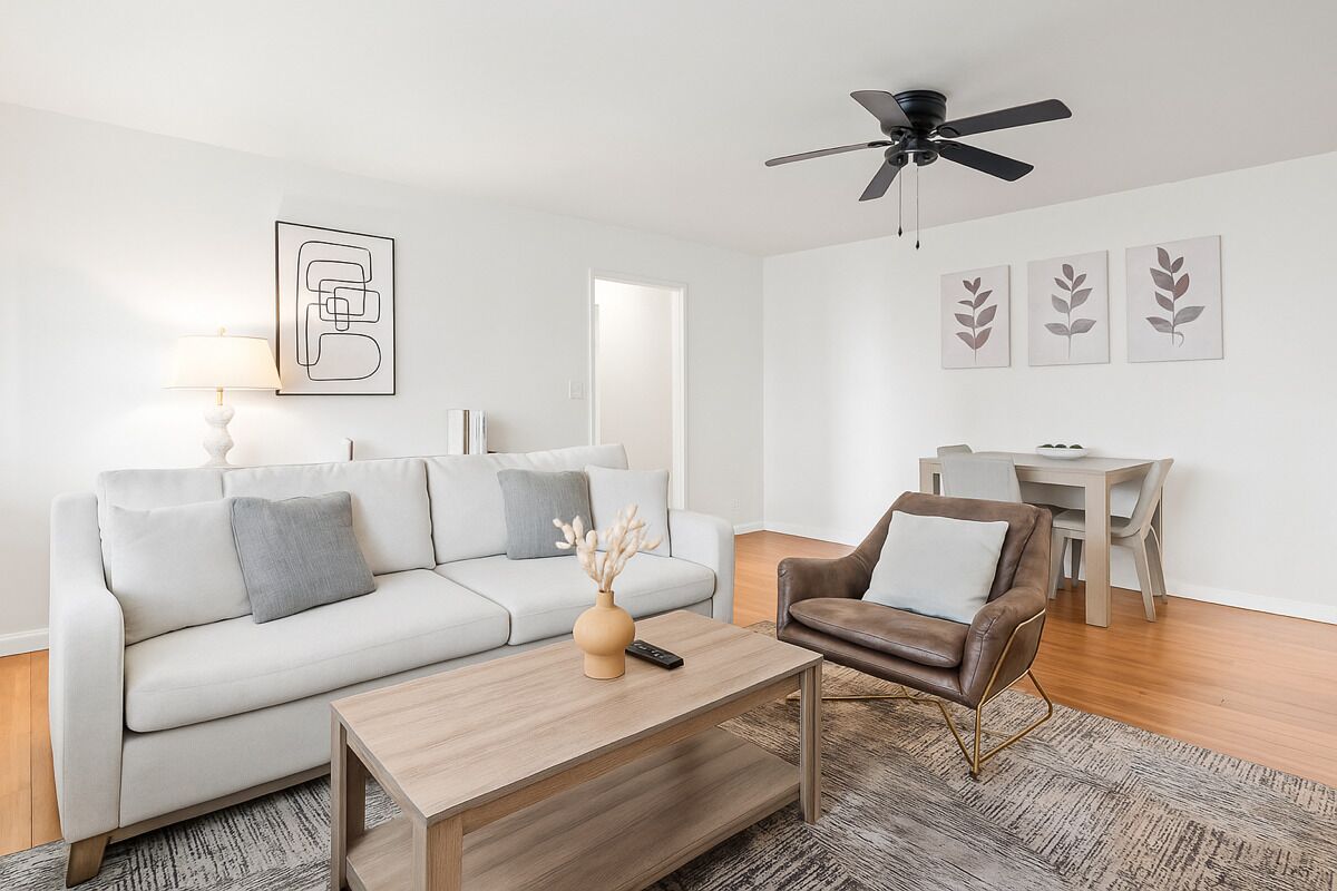 Una sala de estar moderna con un sofá, un sillón, una mesa de centro y un comedor con mesa y sillas.