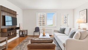 Ein modernes Wohnzimmer mit Flachbildfernseher, einer Couch, einem Couchtisch und einem Sessel.