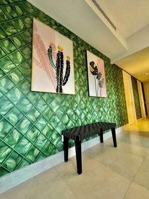 A hallway with a green textured wall, two framed artworks depicting cacti, and a bench. - Fresh Corner of Serenity 3BR. Laguna (Río Hato)