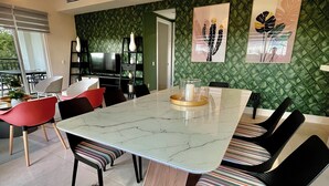 Een eethoek met een marmeren tafel, gestreept bekleden stoelen en hanglampen.