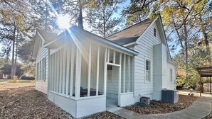 Une maison blanche avec un porche abrité et un petit garage attenant.