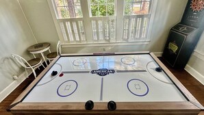 Une table de baby-foot dans une pièce avec une fenêtre, une petite table et une chaise.