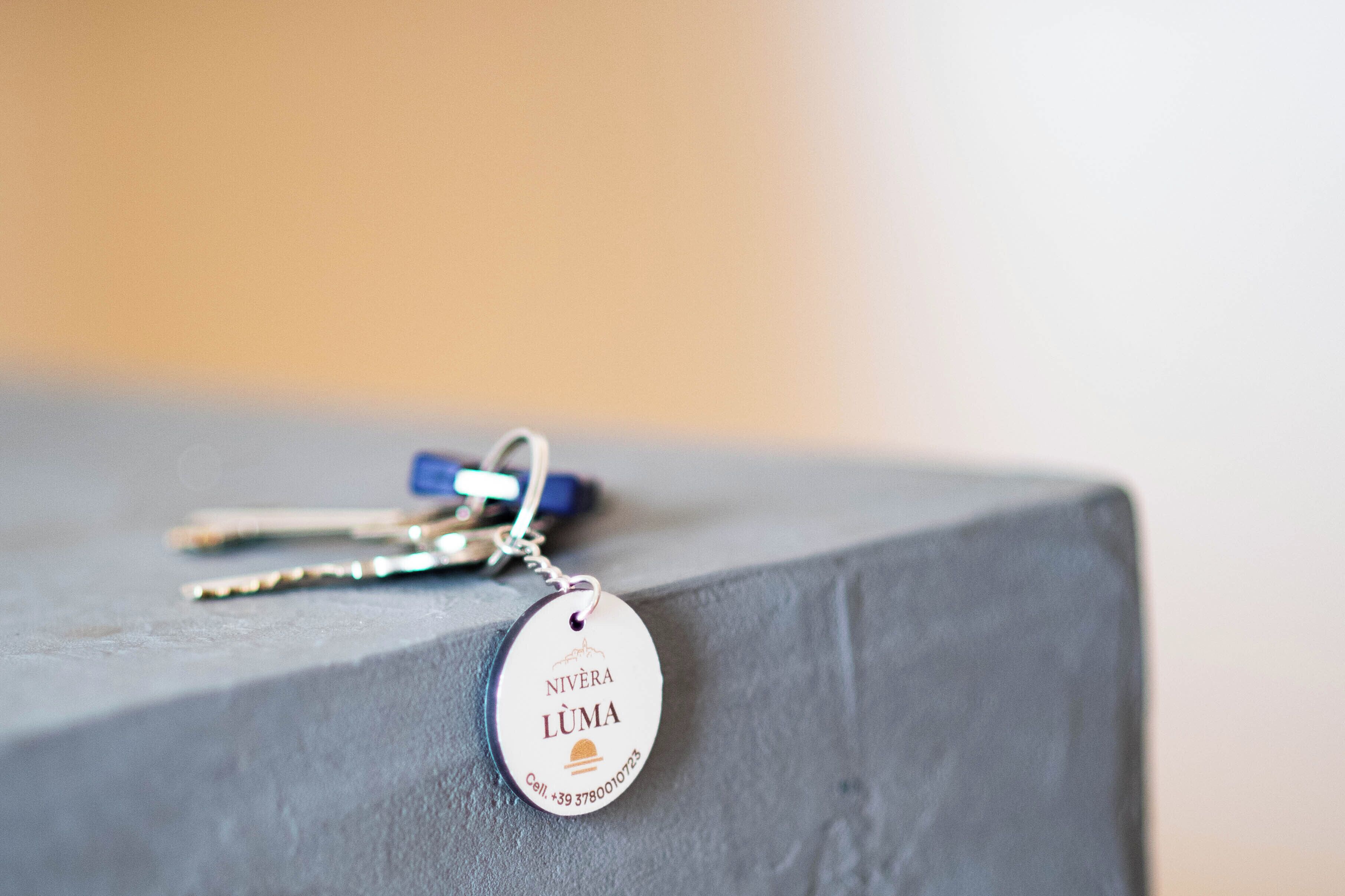 A keychain with a tag that reads "NIVÈRA LUMA" and a phone number.