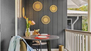 Ein Balkon mit rundem Tisch für zwei Personen, besteckt mit einer Blumenvase und einem Weinglas.