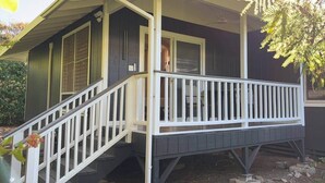 Ein kleines, eingeschossiges Haus mit einer Veranda und einer Treppe zum Eingang.
