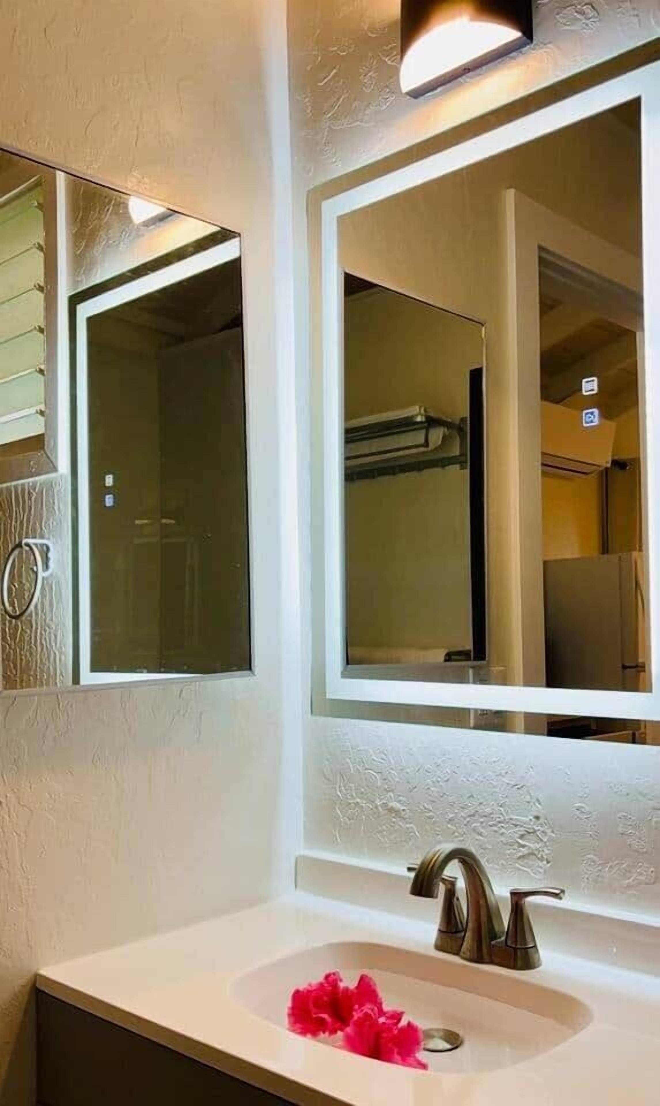 A bathroom with a white sink, a mirror, and a shower door.