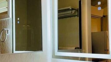 A bathroom with a white sink, a mirror, and a shower door.
