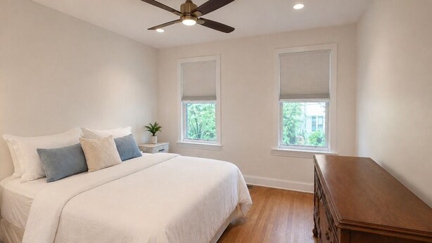 Een slaapkamer met een bed, nachtkastje en een dressoir.
