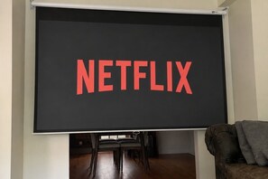 Eine Projektionsleinwand mit dem Wort 'NETFLIX' in roten Buchstaben.