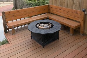 Un banc en bois et un foyer hexagonal sur une terrasse en bois.