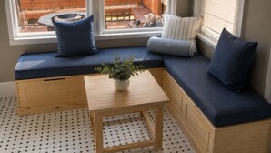 Een zithoek met een bank, een tafeltje en een raam met uitzicht op een terras.