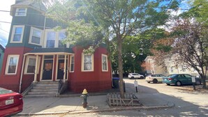 A two-story red building with a black front door and a fire hydrant on the sidewalk. - Kevinsrentals Dot Com (Providence)