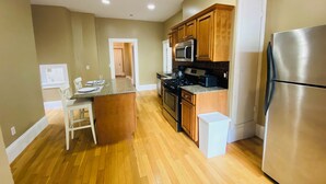 A modern kitchen with wooden cabinets, a stainless steel refrigerator, and a granite countertop. - Kevinsrentals Dot Com (Providence)