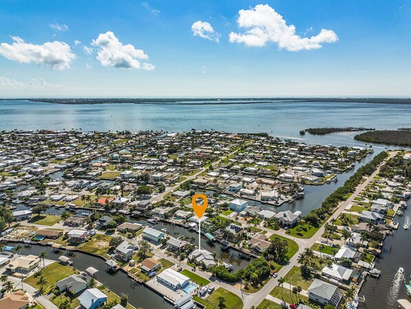 An aerial view of a coastal residential area with numerous houses, a marina, and a clear view of the ocean. - Waterfront Retreat: Charming 2-BR Home w/ AC, Dock & Peaceful. (Saint James City)