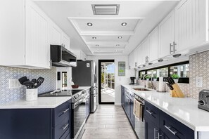 A modern kitchen with white cabinets, stainless steel appliances, and a central island. - Waterfront Retreat: Charming 2-BR Home w/ AC, Dock & Peaceful. (Saint James City)