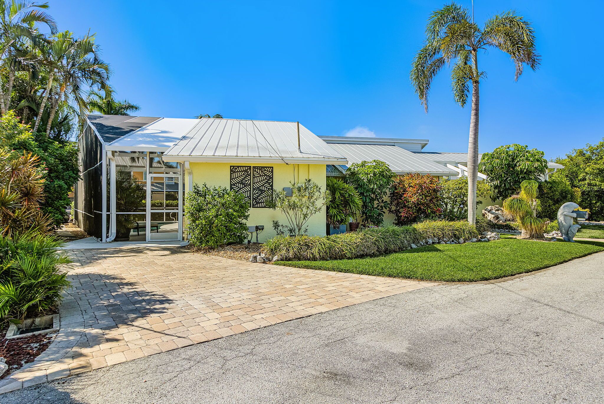 A modern house with a paved driveway, a covered porch, and a well-maintained lawn.