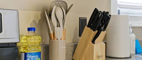 A kitchen counter with a bottle of vegetable oil, a utensil holder, and a knife block.