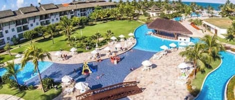 Un resort con una grande piscina, palme e una zona spiaggia.