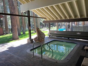 A covered outdoor swimming pool with a bench, a covered area, and trees in the background. - Cal King, 2BR/2bth Hot Tub, Pool & Walk to town (Mammoth Lakes)