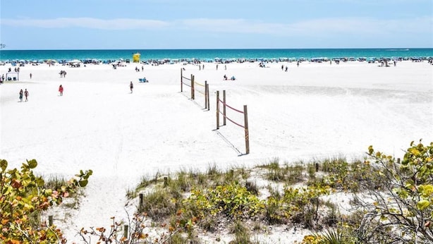 A beach with a sandy area and a wooden fence in the foreground.