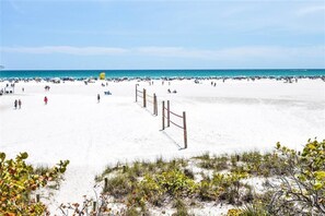 A beach with a sandy area and a wooden fence in the foreground.