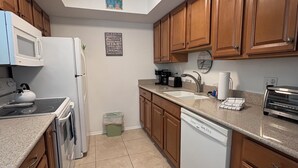 A kitchen with wooden cabinets, a microwave, a stove, a dishwasher, and a sink.