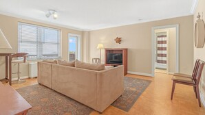 Ein Wohnzimmer mit einem beigefarbenen Sofa, einem Fernseher, einer Lampe und einer Holzkassette.