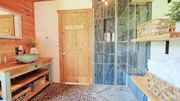 Un bagno in legno con doccia, lavabo e ripiano con articoli da toilette.