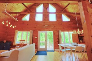 A wooden cabin with a loft bedroom, a dining area, and a kitchen. - Full Guest Suite (Wakefield)