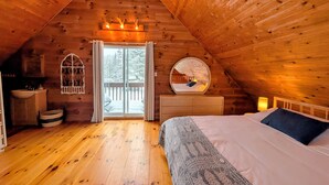 A cozy attic bedroom with a wooden ceiling, a large bed, a dresser, a round mirror, and a window with curtains. - Private Escape For 2 (Wakefield)