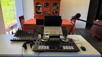 Configuración de estudio en casa con una computadora portátil, mezcladora de audio y auriculares sobre una mesa.