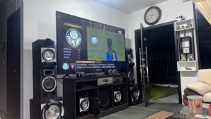 A living room with a large flat-screen TV mounted on a black entertainment unit, surrounded by multiple speakers. - Villa Mariaclaudia Macas (Macas)