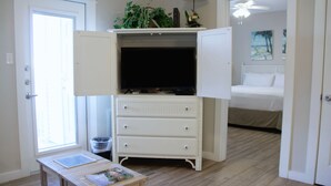 A bedroom with a bed, a white wardrobe, a small table with a book, and a window. - Compass Bayfront Condo, Close to Beach & Pool! (Corpus Christi)
