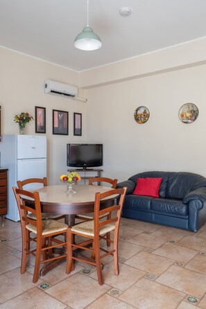 Un comedor con una mesa redonda, sillas, un televisor y un sofá.