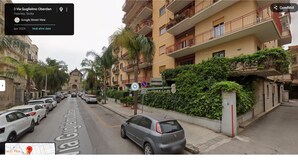 En gatubild från Via Guglielmo Oberdan i Palermo, Sicilien, med parkerade bilar och en byggnad med balkonger och grönska.