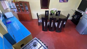 Een kleine keuken met een gasfornuis, een eettafel met stoelen, een koelkast en een magnetron.