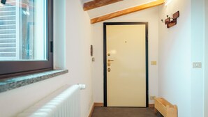 Un pasillo estrecho con un banco de madera, un radiador y una puerta con interruptor de luz encima.