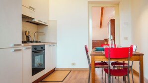 Una cocina moderna con armarios blancos, una estufa y una zona de comedor con una mesa de madera y sillas rojas.