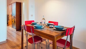 Una mesa de comedor con sillas rojas, cuencos azules y una botella.