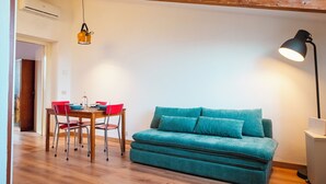 Una habitación acogedora con una mesa de comedor de madera, sillas rojas, un sofá color turquesa y una lámpara de pie negra.