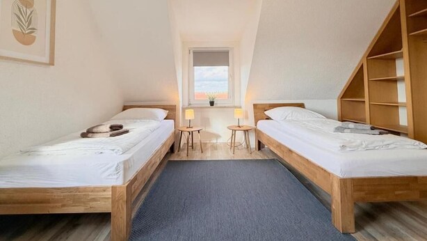 Ein Zimmer mit zwei Holzbetten, einem kleinen Tisch und einem Fenster.